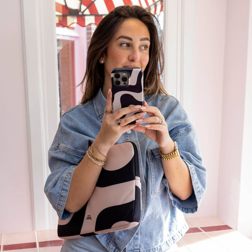 Vrouw met 13-14 inch laptop sleeve "Ride With Me" in zwart-roze abstract design, passend bij telefoonhoesje.