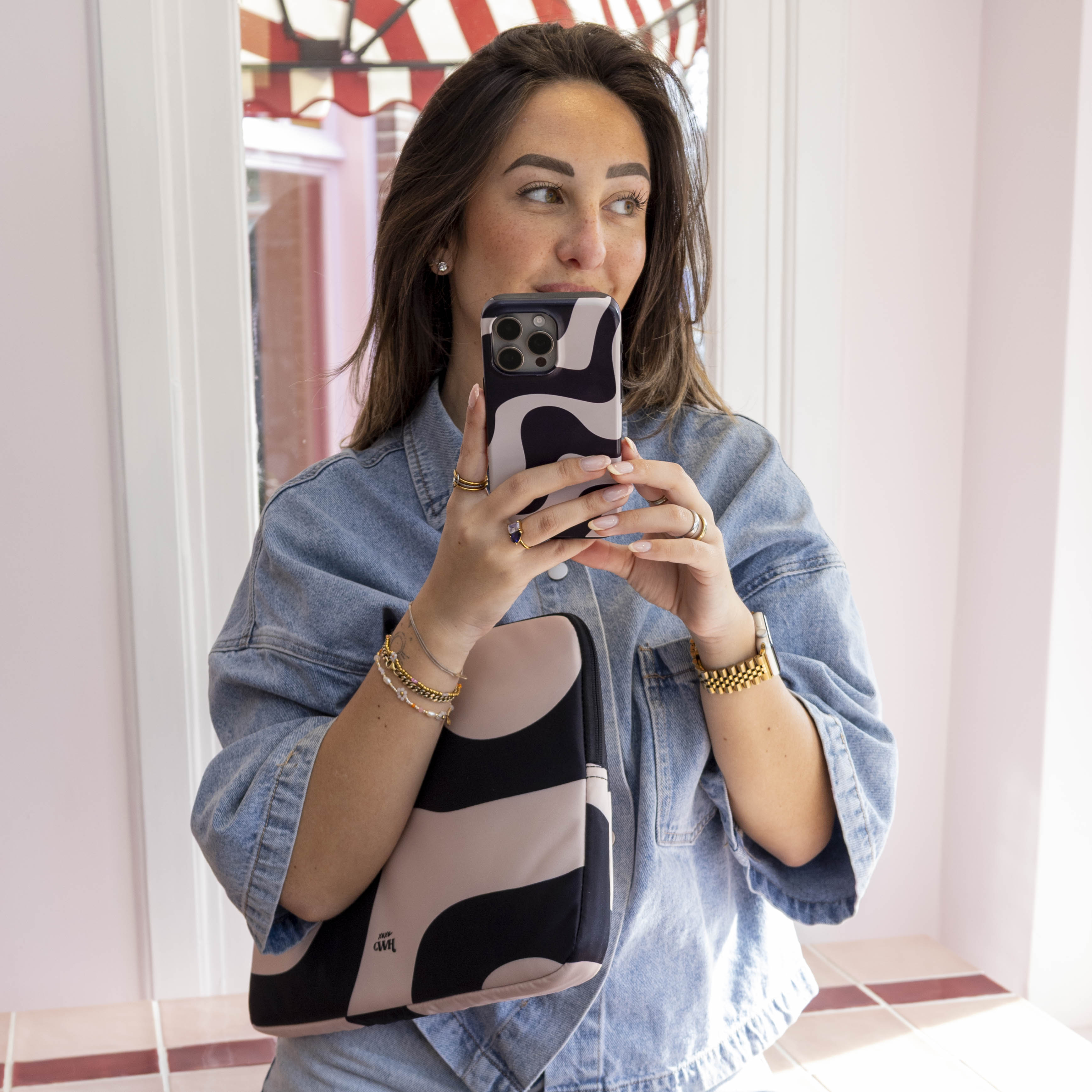 Vrouw met 13-14 inch laptop sleeve "Ride With Me" in zwart-roze abstract design, passend bij telefoonhoesje.