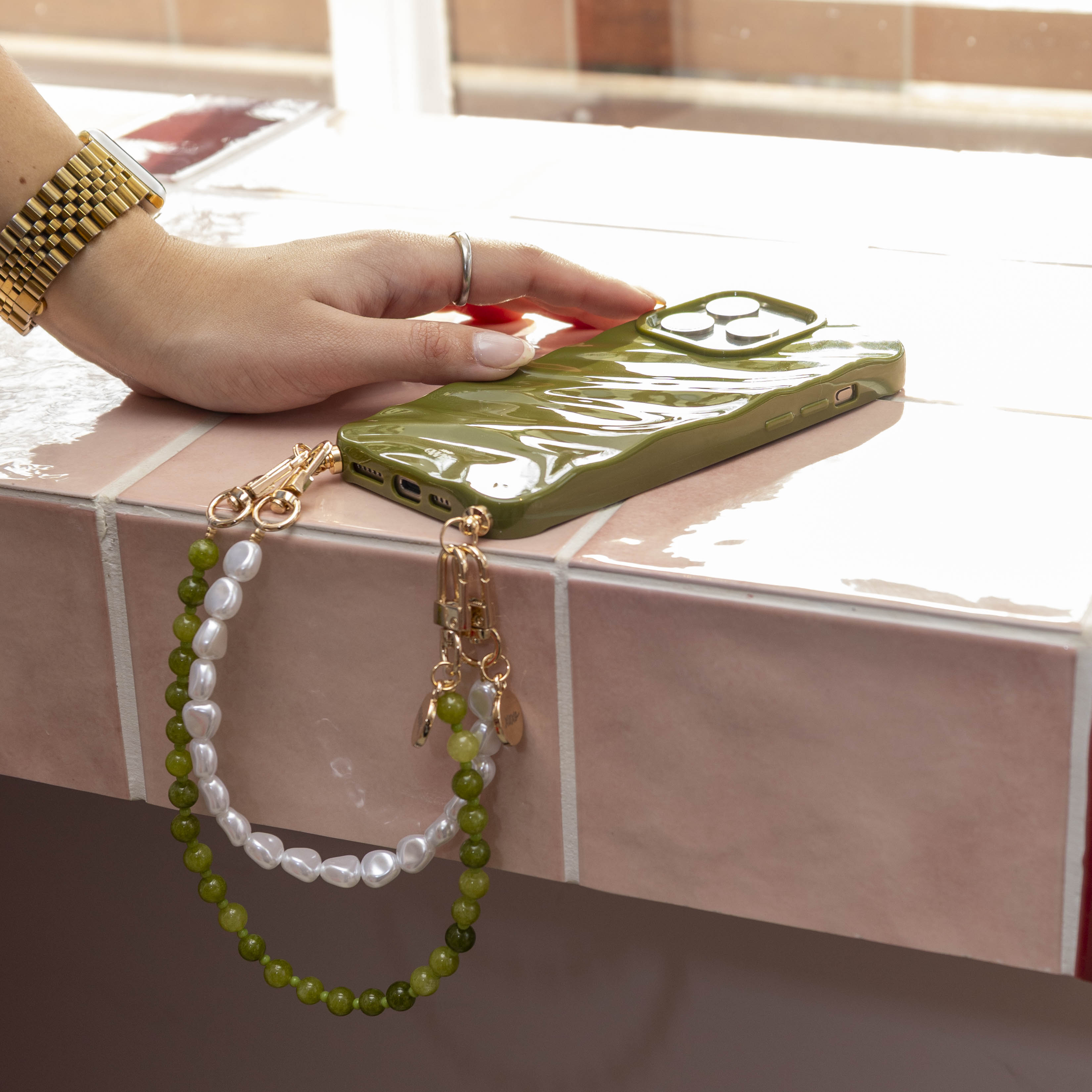 Glanzende donkergroene iPhone 11 hoes met twee koorden: een kort Deep Olives en een wit parelkoord.