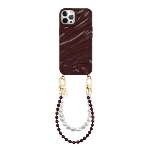 Burgundy Glaze Cord iPhone 12 Pro Max case with shiny wavy texture, gold hardware, and pearl wrist strap.