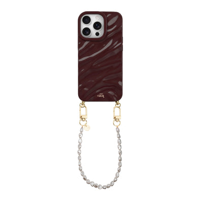 Bordeauxrode glanzende telefoonhoes met golvend patroon en korte parelketting met gouden sluitingen.