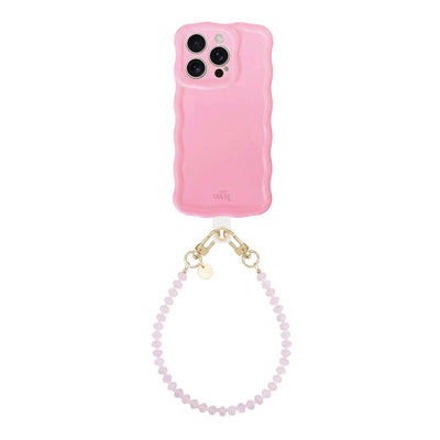 Glossy wavy bubble blush iPhone 13 Pro case with a short dusty pink beaded wrist cord.
