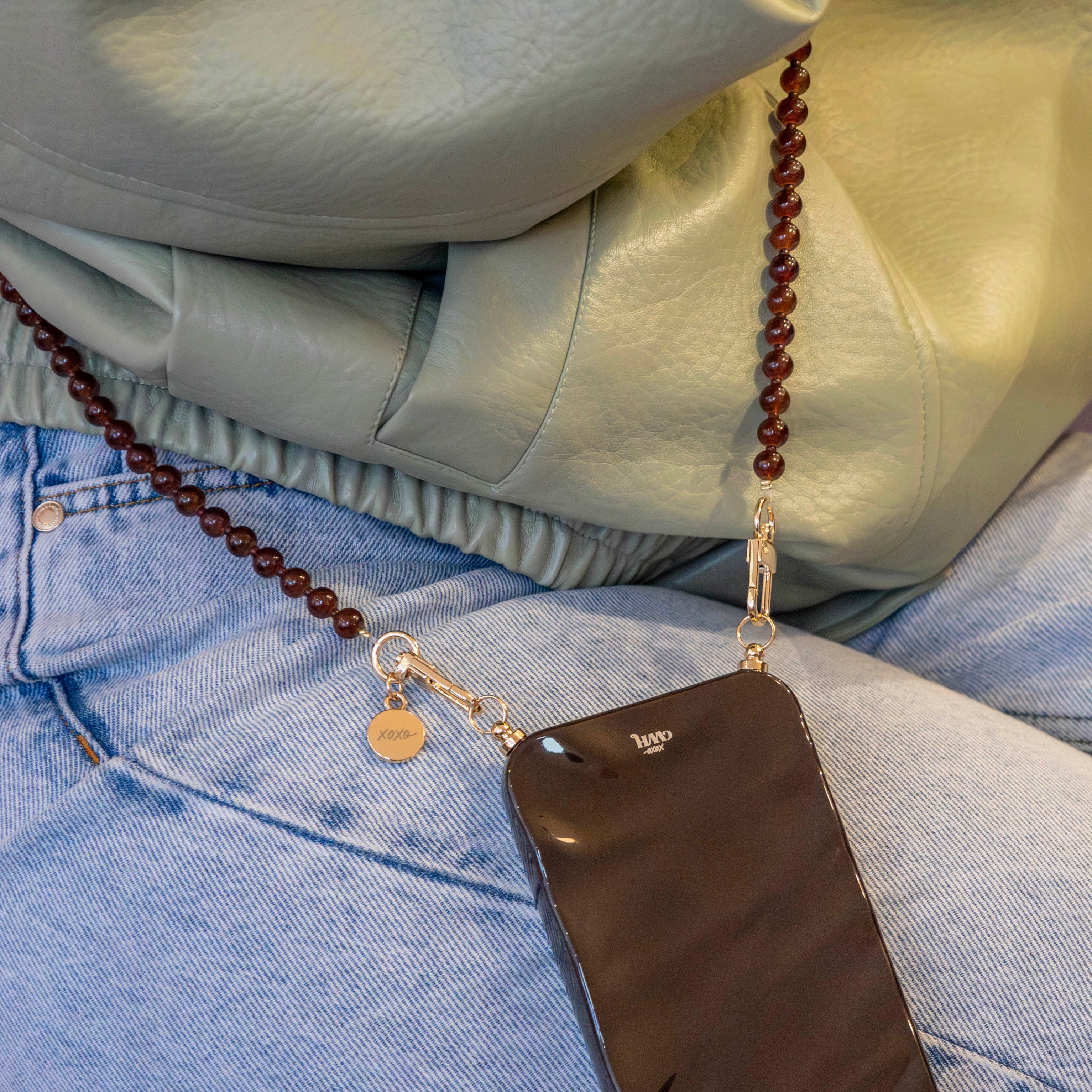 Glanzende bruine iPhone 15 Plus Glaze Cord Case met lange Brown Sugar kralenkoord en gouden details.