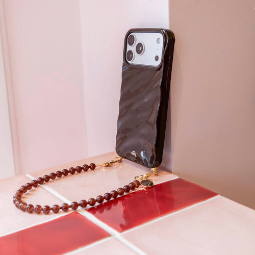 Glanzend bruin iPhone 12 hoesje met golvend design en bijpassend kort Brown Sugar kralenkoord.