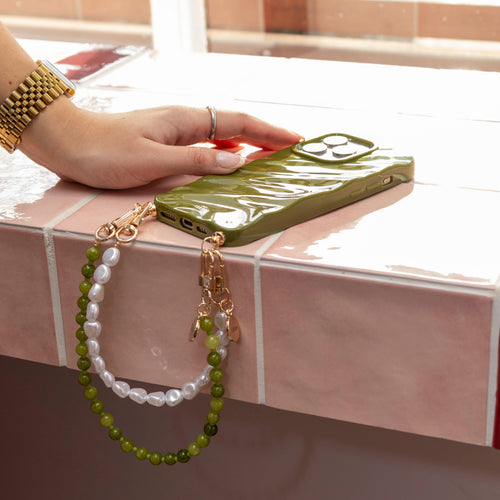 Glanzende donkergroene iPhone 11 hoes met twee koorden: een kort Deep Olives en een wit parelkoord.