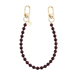 Kort Burgundy Muse koord met glanzende bordeauxrode kralen en twee gouden karabijnhaken.