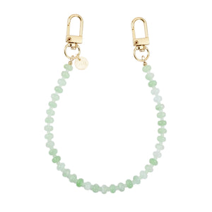 Kort Dusty Green kralenkoord voor telefoon met gouden karabijnhaken en merklabel.