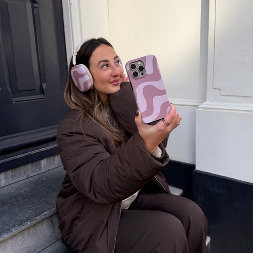 Vrouw met AirPods Max (2) in Ride With Me Brown covers en bijpassend telefoonhoesje.