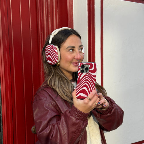 Vrouw met AirPods Max covers in rood-wit Boogie Wonderland design en bijpassend telefoonhoesje.