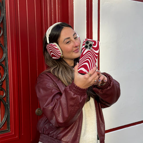 Vrouw met AirPods Max met rood-witte Boogie Wonderland covers en bijpassend telefoonhoesje.