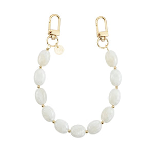 Kort Ocean Sand polskoord met witte ovale kralen, gouden details en twee karabijnsluitingen.
