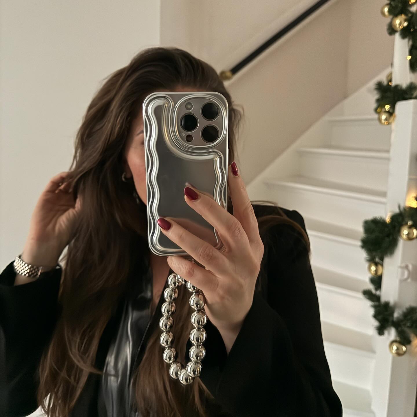 Silver wavy iPhone case with a matching silvery beaded easy cord held by a person.